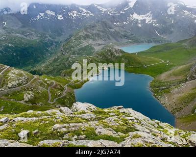 Vista dal punto panoramico a Colle del Nivolet sul Lago Agnel di fronte, Lago Serru sul retro, sulle serpentine di sinistra del passo strada sopra la linea degli alberi Foto Stock