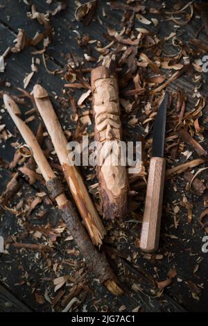 Gancio a crochet intagliato e il volto di un vecchio uomo, coltello da intaglio e trucioli di legno Foto Stock