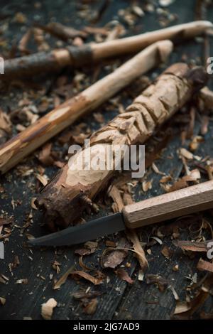 Gancio a crochet intagliato e il volto di un vecchio uomo, coltello da intaglio e trucioli di legno Foto Stock