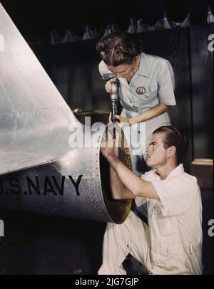 La sig.ra Virginia Davis, un rivettatore nel reparto di assemblaggio e riparazione della base aerea navale, supervisiona il Chas. Potter, un tirocinante DI NYA dal Michigan; Corpus Christi, Texas. Foto Stock