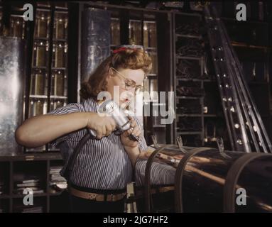 Il funzionamento di un trapano a mano presso la North American Aviation, Inc., [a] donna sta lavorando in superficie di controllo reparto assemblaggio di una sezione del bordo di attacco per il empennage orizzontale di un piano, Inglewood, Calif. Foto Stock