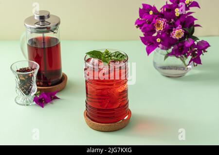 Tè di frutta rossa ghiacciata appena fatto su un tavolo verde Foto Stock