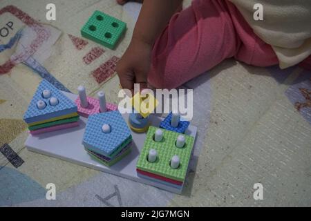 La mano del bambino, giocando con i giocattoli di montessory. Puzzle geometrico. Educazione per i bambini che cerca di sviluppare interessi e attività naturali. Foto Stock