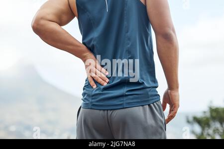 Mi sono sentito davvero questo alle mie spalle. Scatto di un giovane sportivo che avverte dolore alla schiena mentre fuori per una corsa. Foto Stock