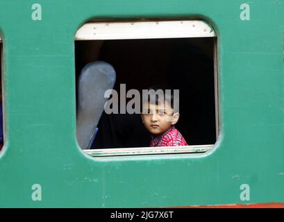 Le persone in casa aspettano il treno mentre viaggiano verso i loro villaggi, prima delle celebrazioni di Eid-al-Adha alla stazione ferroviaria di Dhaka, Bangladesh su J Foto Stock