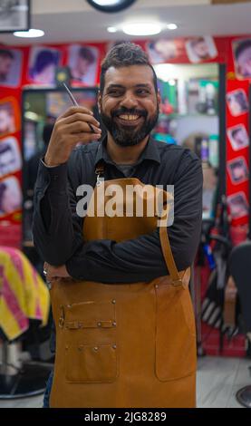 Felice ritratto uomo arabo barbiere con forbici Foto Stock