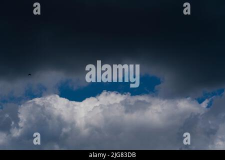 Nuvole di pioggia grigie e bianche, nel cielo blu medio e uccelli Foto Stock