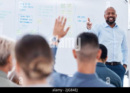Il team di formazione e di insegnamento dei manager aziendali afroamericani maturi in ufficio. Uomo d'affari nero che usa una lavagna per parlare e spiegare Foto Stock