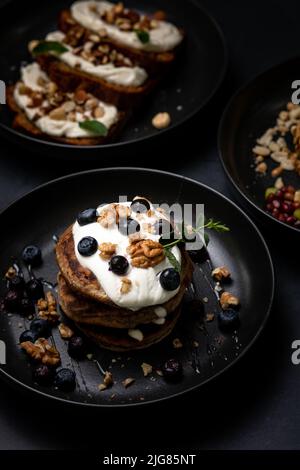 Colazione perfetta, pancake americani accatastati su un tavolo di pietra nera. Deliziosi pancake americani accatastati con mirtillo, da vicino, vista dall'alto. Foto Stock