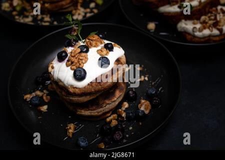 Colazione perfetta, pancake americani accatastati serviti su un tavolo di pietra nera. Foto Stock