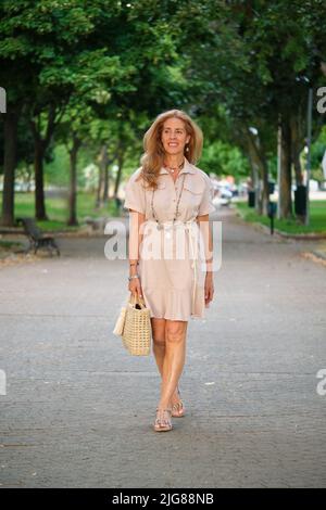 Ritratto a tutta lunghezza da esterno di donna sorridente bionda matura e con occhi blu. Foto Stock
