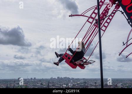 Paesi Bassi, Amsterdam: La giovane donna oscilla ad un'altezza di 100 metri sopra Amsterdam. "Over the Edge" è l'altalena più alta d'Europa e una popolare attrazione turistica nel quartiere Noord di Amsterdam. Foto Stock
