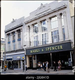 Marks and Spencer, 17-23 New Street, Huddersfield, Kirklees, 1970s-1990s. Le elevazioni frontali dei negozi di Burton e Marks e Spencer, progettati in modo simile, sono al 17-23 di New Street. Marks e Spencer si trasferirono da un sito esistente a Huddersfield all'ex locale di Burton al 19-23 New Street nel 1934. Burton ha acquisito il sito d'angolo, a 17 New Street, e ha costruito un negozio più piccolo di un design quasi identico. Il negozio Burton aveva chiuso entro il 2008 e i locali erano occupati da Vision Express. I Marks e Spencer chiuse nel 2019. Foto Stock