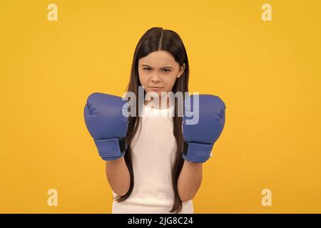 bambino aggressivo in guanti da boxe su sfondo giallo Foto Stock