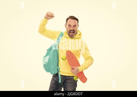 l'uomo felice maturo porta lo zaino e il bordo del penny. ragazzo anziano sorridente di nuovo a scuola Foto Stock