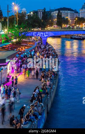 Vienna, fiume Donaukanal (canale del Danubio), la gente si siede sul rinforzo della banca, ristoranti all'aperto e bar nel 01. Distretto Città Vecchia, Vienna, Austria Foto Stock