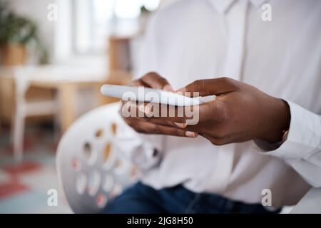 Tenendosi aggiornati sulle ultime tendenze. Scatto di una donna d'affari irriconoscibile che usa uno smartphone in un ufficio moderno. Foto Stock