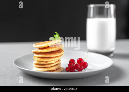 Mini pancake con mirtilli e lamponi. Colazione all'americana su sfondo scuro. Alimentazione sana per tutta la famiglia. Pancake fatti in casa con Foto Stock