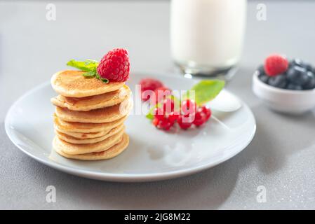 Pancake con frutti di bosco su un piatto bianco. American Pancake Mini Pancakes con frutti di bosco Foto Stock