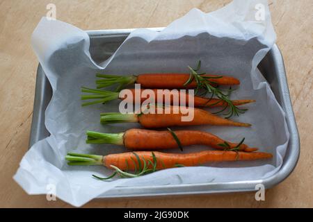 Carota intera giovane con verdure in teglia da forno Foto Stock