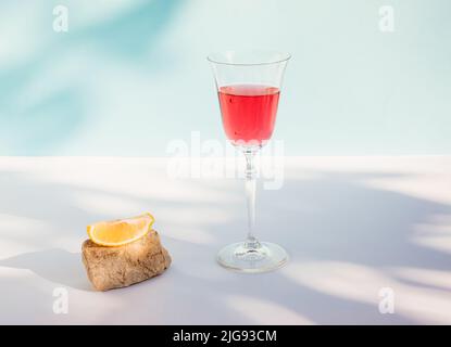 Composizione estiva creativa con bevanda rossa fresca, fetta di limone, pietra e ombra. Bevanda estiva minimale concetto. Foto Stock