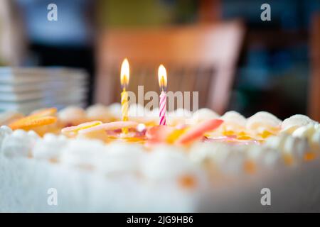 Torta di compleanno colorata con due candele accese Foto Stock