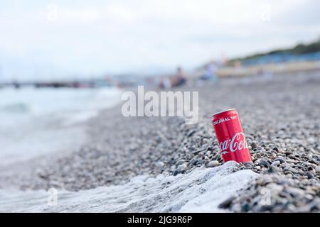 ANTALYA, TURCHIA - 18 MAGGIO 2021: L'originale lattina rossa Coca Cola si trova su piccole pietre di ciottoli rotonde vicino al mare. Coca-cola sulle pietre della spiaggia turca Foto Stock