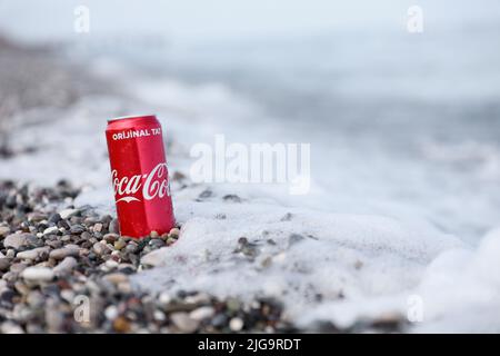 ANTALYA, TURCHIA - 18 MAGGIO 2021: L'originale lattina rossa Coca Cola si trova su piccole pietre di ciottoli rotonde vicino al mare. Coca-cola sulle pietre della spiaggia turca Foto Stock