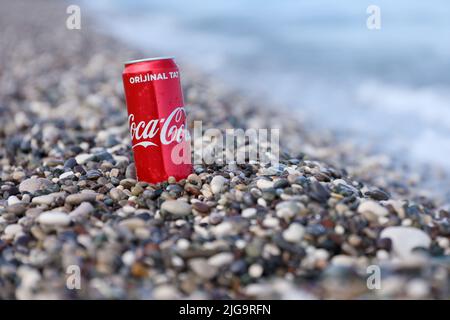 ANTALYA, TURCHIA - 18 MAGGIO 2021: L'originale lattina rossa Coca Cola si trova su piccole pietre di ciottoli rotonde vicino al mare. Coca-cola sulle pietre della spiaggia turca Foto Stock