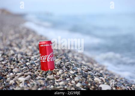 ANTALYA, TURCHIA - 18 MAGGIO 2021: L'originale lattina rossa Coca Cola si trova su piccole pietre di ciottoli rotonde vicino al mare. Coca-cola sulle pietre della spiaggia turca Foto Stock