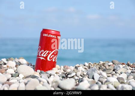 ANTALYA, TURCHIA - 18 MAGGIO 2021: L'originale lattina rossa Coca Cola si trova su piccole pietre di ciottoli rotonde vicino al mare. Coca-cola sulle pietre della spiaggia turca Foto Stock