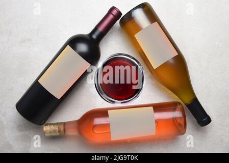 Cabernet, Rose, Chardonnay: Vista dall'alto di un gruppo di tre bottiglie diverse con etichette bianche disposte a triangolo con un bicchiere di vino nel m Foto Stock