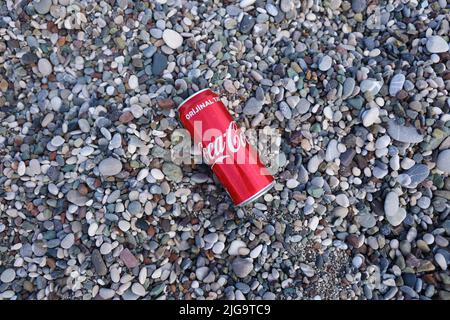 ANTALYA, TURCHIA - 18 MAGGIO 2021: L'originale lattina rossa Coca Cola si trova su piccole pietre di ciottoli rotonde vicino al mare. Coca-cola sulle pietre della spiaggia turca Foto Stock