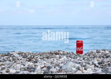 ANTALYA, TURCHIA - 18 MAGGIO 2021: L'originale lattina rossa Coca Cola si trova su piccole pietre di ciottoli rotonde vicino al mare. Coca-cola sulle pietre della spiaggia turca Foto Stock