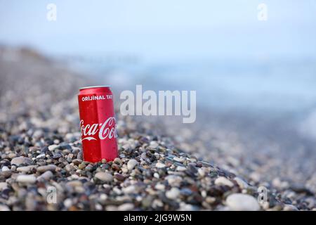 ANTALYA, TURCHIA - 18 MAGGIO 2021: L'originale lattina rossa Coca Cola si trova su piccole pietre di ciottoli rotonde vicino al mare. Coca-cola sulle pietre della spiaggia turca Foto Stock