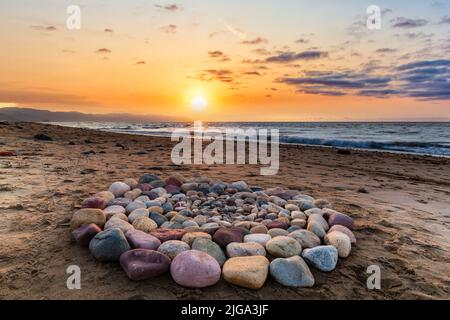 Le pietre rituali per la cerimonia spirituale sono organizzate in un cerchio durante il tramonto sulla spiaggia Foto Stock