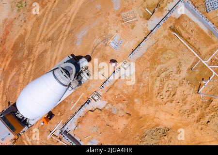Lavoratori che versano colonne in calcestruzzo su una nuova struttura in cantiere Foto Stock