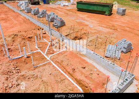 Posa di fognature e tubi dell'acqua sotto la fondazione di una nuova casa di costruzione residenziale Foto Stock