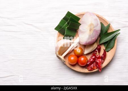 verdure, ingredienti aromatizzanti comuni per la cucina asiatica e sud-asiatica, erbe e spezie per cucinare su un piatto di legno, isolato Foto Stock