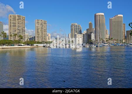 Appartamenti o quartieri d'affari accanto ad un porto in una giornata di sole con un cielo blu nuvoloso. Una popolare località turistica estiva alle Hawaii. Lusso Foto Stock