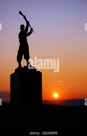 Il Memorial alla fanteria della Pennsylvania del 72nd presso il campo di battaglia della Guerra civile americana a Gettysburg raffigura un soldato che oscilla il suo fucile al tramonto Foto Stock