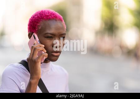 Afrodonna con un'espressione diffidente che parla su un cellulare Foto Stock