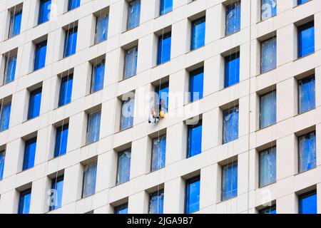 gruppo di rondelle per finestre appese su funi su una facciata grattacielo Foto Stock