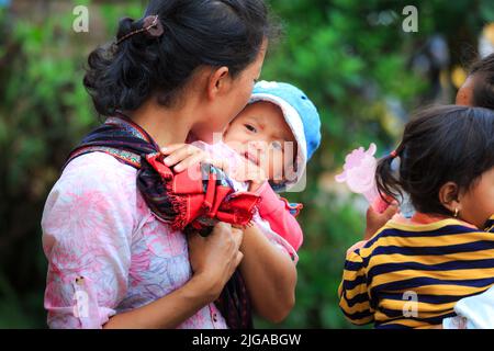 Le donne di minoranza etnica trasportano i loro bambini con le grandi sciarpe Foto Stock