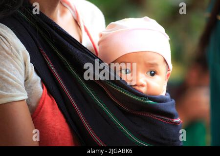 Le donne di minoranza etnica trasportano i loro bambini con le grandi sciarpe Foto Stock