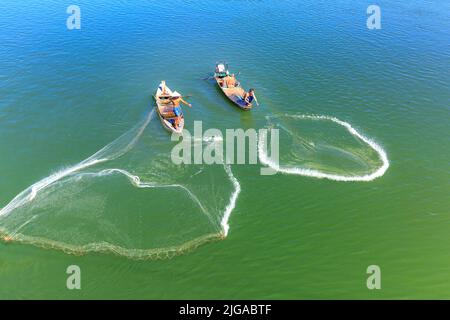 Di una rete di colata per la cattura di pesci su tri di un lago. Questo è il lavoro quotidiano di persone dal villaggio di pescatori di lakeside Foto Stock