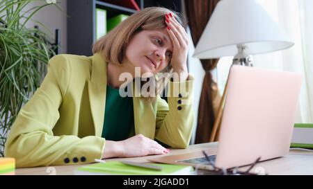 Donna stanca che lavora con un moderno notebook in ufficio Foto Stock