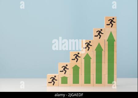 scala di successo. frecce su che mostrano crescita e silhouette uomo su cubi di legno. Concetto di successo e il raggiungimento del vostro obiettivo. Percorso carriera scala per autobus Foto Stock