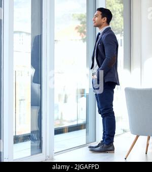 La mia città ha bisogno di me, un uomo d'affari che guarda fuori la sua finestra d'ufficio. Foto Stock