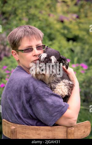 Donna con il suo cane schnauzer in miniatura seduto all'aperto Foto Stock